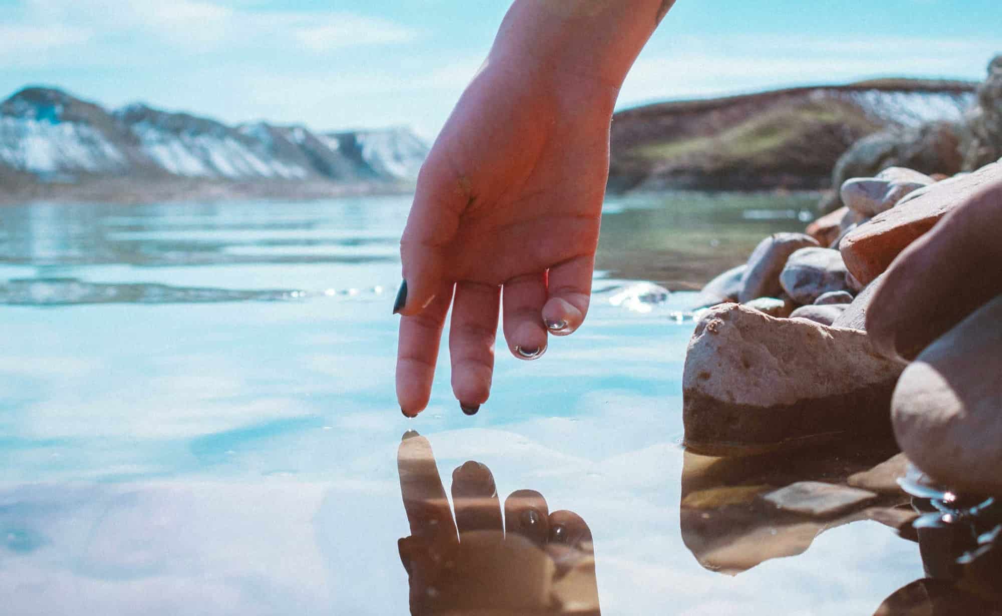hand reaching toward water reflection